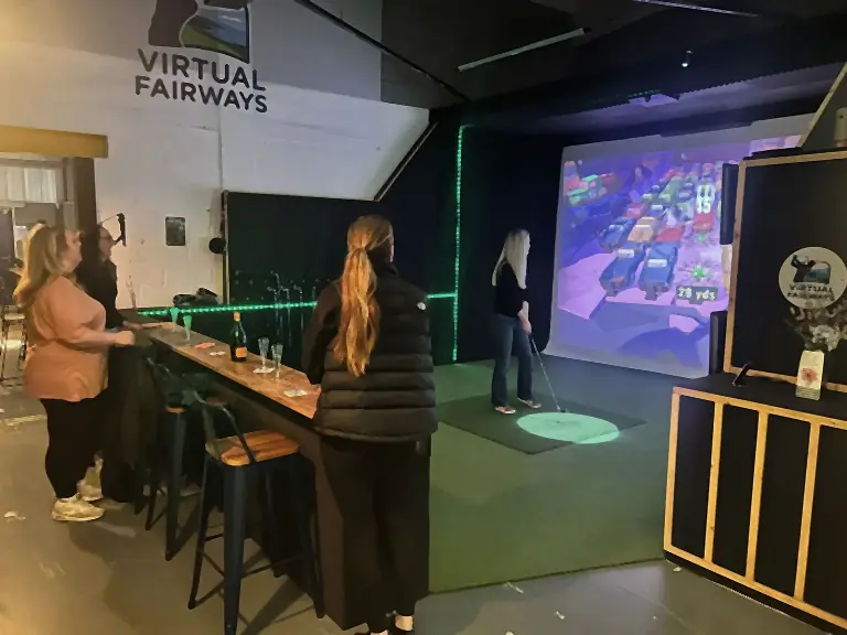 A group laughing together in a simulator bay at Virtual Fairways, Darlington